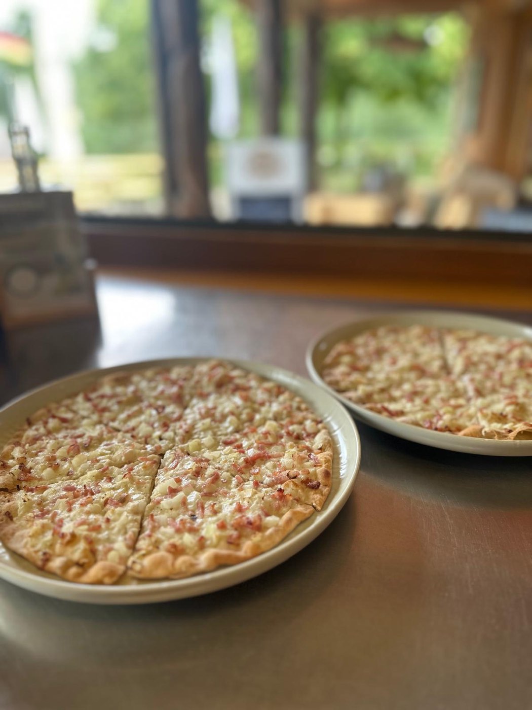 Frisch gebackener Flammkuchen auf zwei Tellern