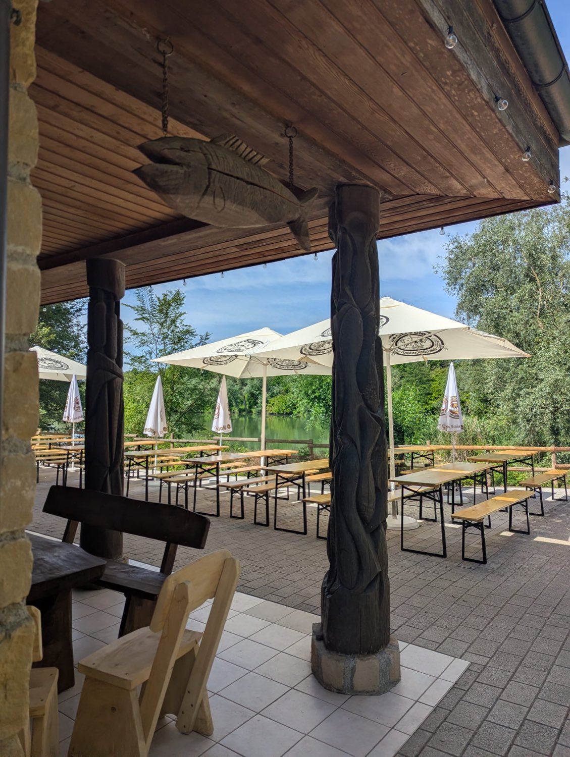 Überdachter Festbereich mit geschnitzten Holzsäulen und Seeblick