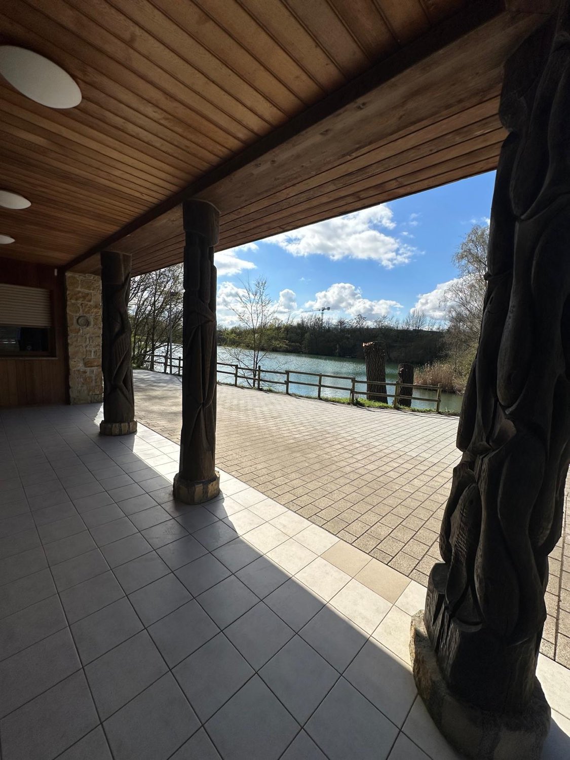 Überdachte Terrasse mit geschnitzten Holzsäulen und Blick auf den See